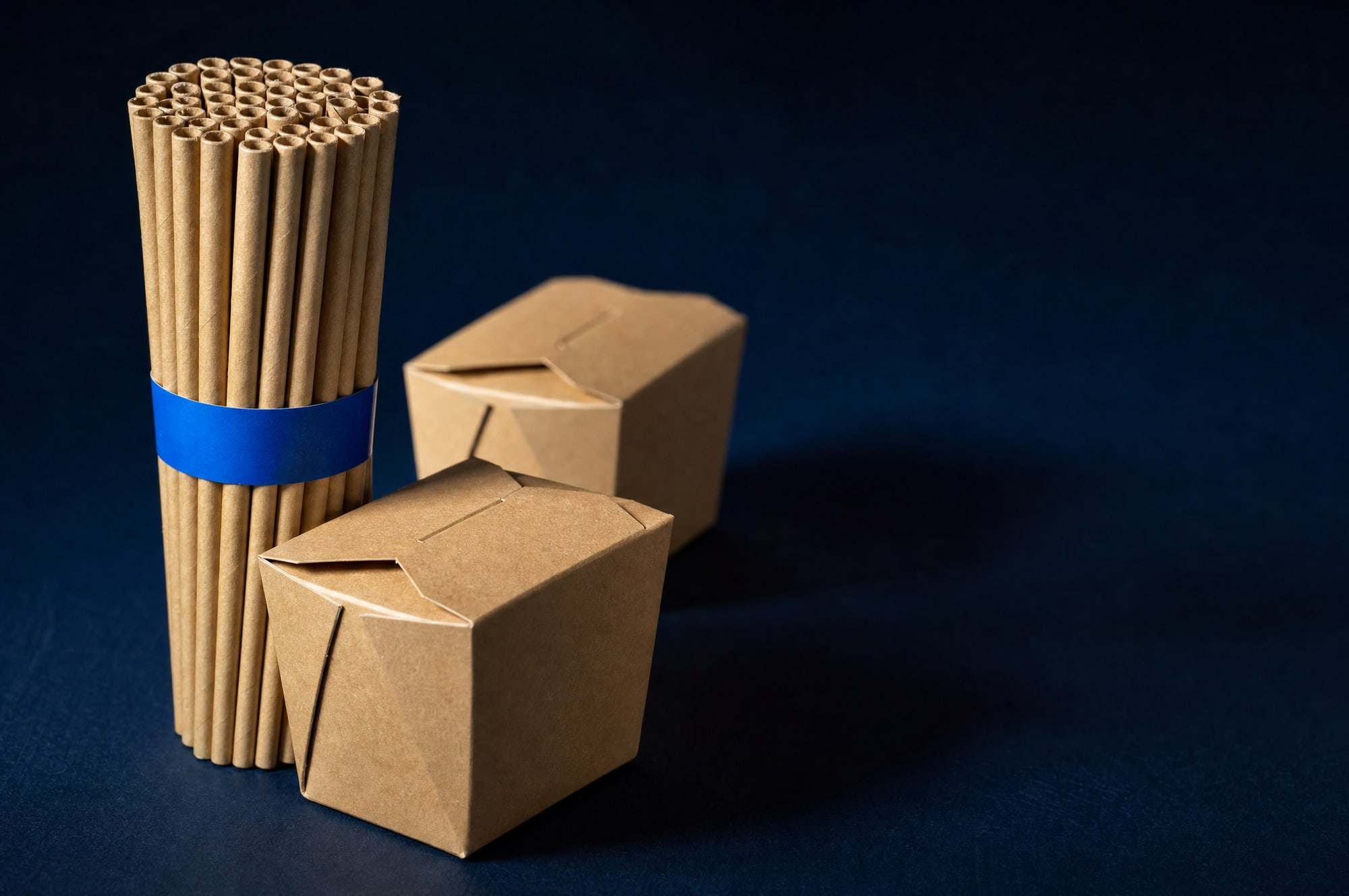 Bundled paper straws and small kraft boxes.