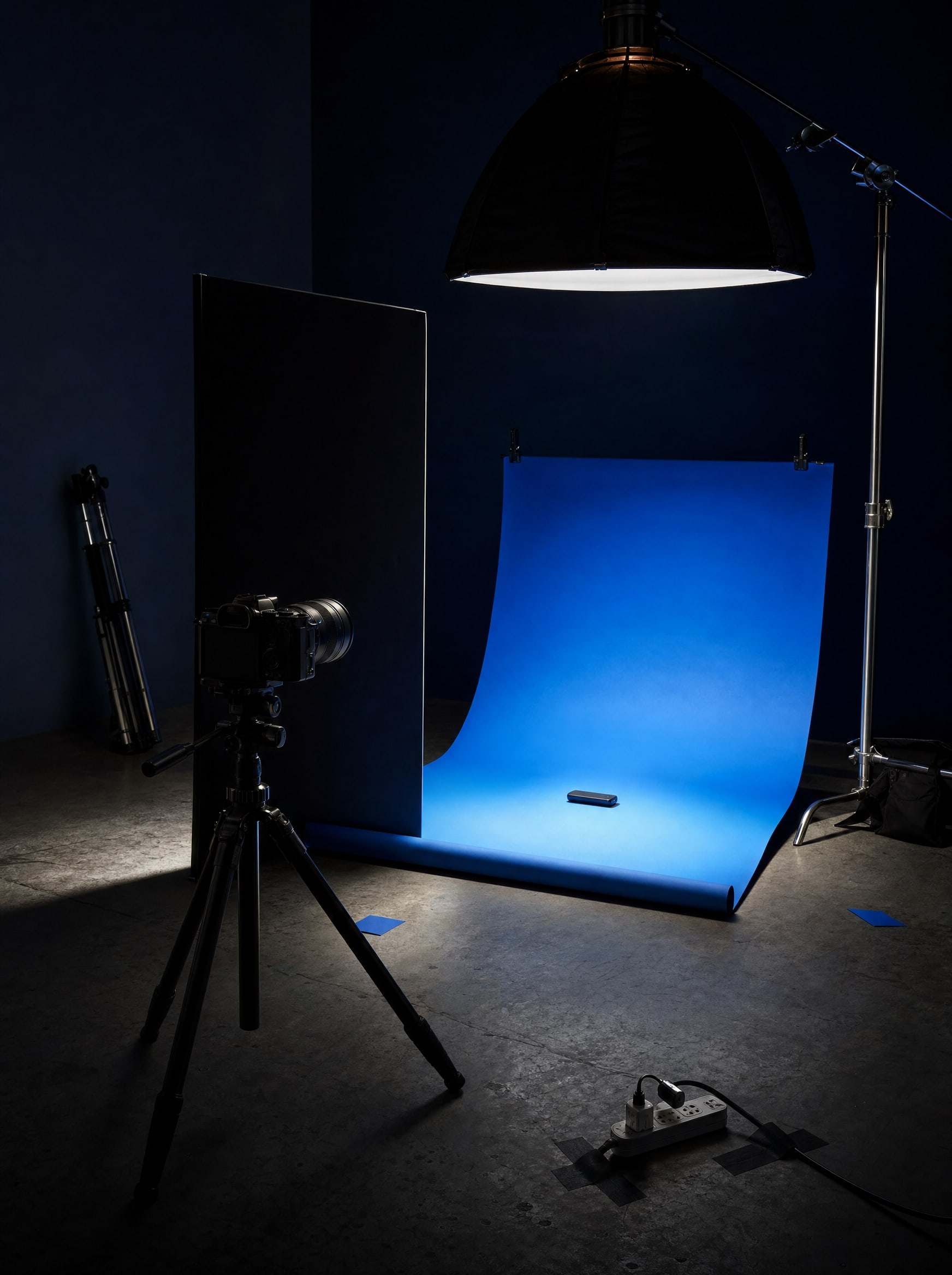 Kobalt kâğıt fonlu fotoğraf stüdyosunda tripod üzerinde kamera.